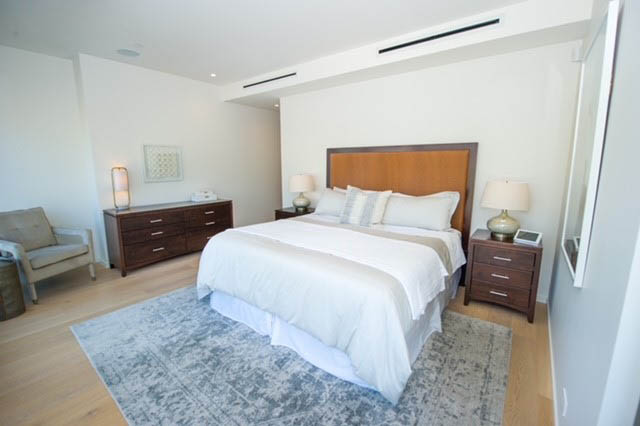 Spacious bedroom with hardwood floors, large bed, and modern furnishings. - 601 - 1355 Bellevue Ave, West Vancouver