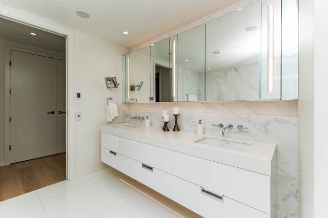 Bright bathroom with marble countertops and large mirror. - 601 - 1355 Bellevue Ave, West Vancouver