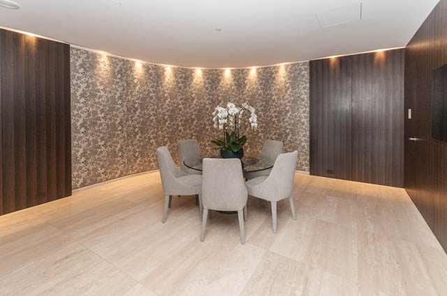 Furnished dining area with curved wall, modern chairs, and orchid centerpiece. - 601 - 1355 Bellevue Ave, West Vancouver