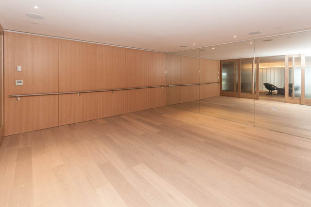 Bright living room with hardwood floors and mirrored walls. - 601 - 1355 Bellevue Ave, West Vancouver