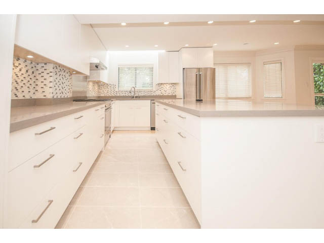 Bright kitchen with white cabinetry, granite countertops, and large island. - 4428 Marine Drive, West Vancouver