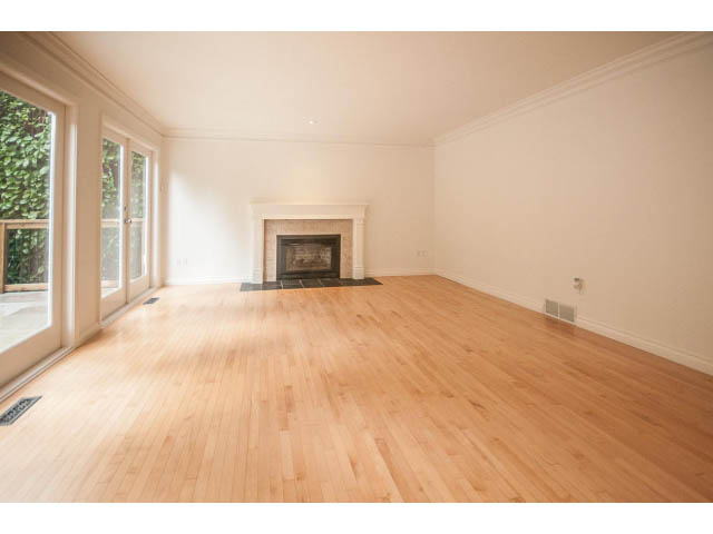 Bright living room with hardwood floors and a fireplace, leading to a patio. - 4428 Marine Drive, West Vancouver