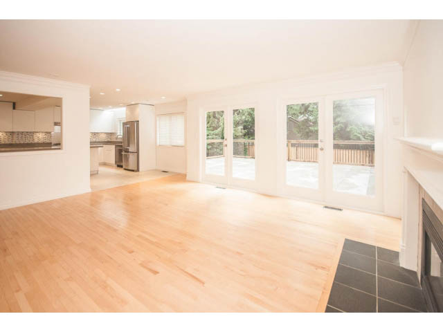 Bright open-concept living space with hardwood floors and large windows leading to a deck. - 4428 Marine Drive, West Vancouver