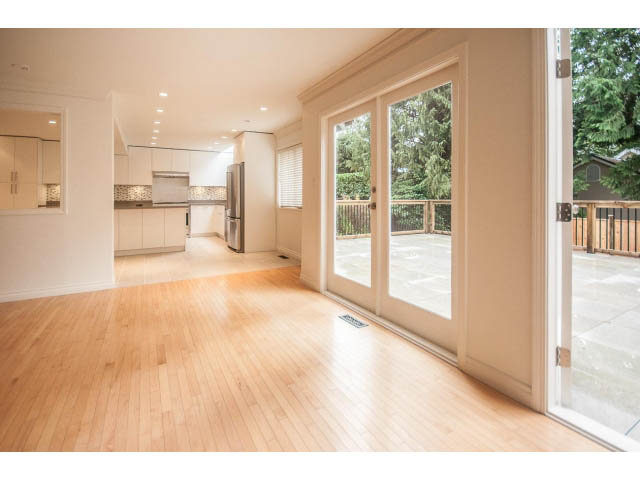 Bright kitchen with hardwood floors and large windows, offering a view of the greenery outside. - 4428 Marine Drive, West Vancouver