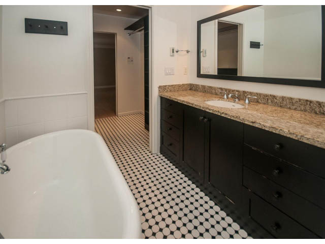 Spacious bathroom with black cabinets, granite countertops, and black-and-white penny tile floor. - 4428 Marine Drive, West Vancouver