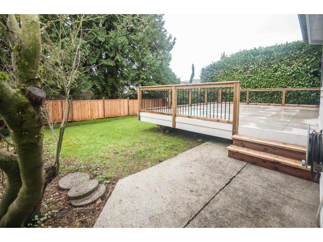 Furnished patio with wooden deck and concrete path leading to grassy area. - 4428 Marine Drive, West Vancouver
