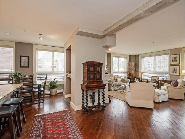 Open-concept living space with hardwood floors, large windows, and a central wooden table. - 509 - 1216 Homer Street, Vancouver Downtown