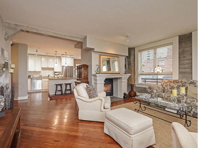 Open-concept living space with hardwood floors and a kitchen in the background. - 509 - 1216 Homer Street, Vancouver Downtown