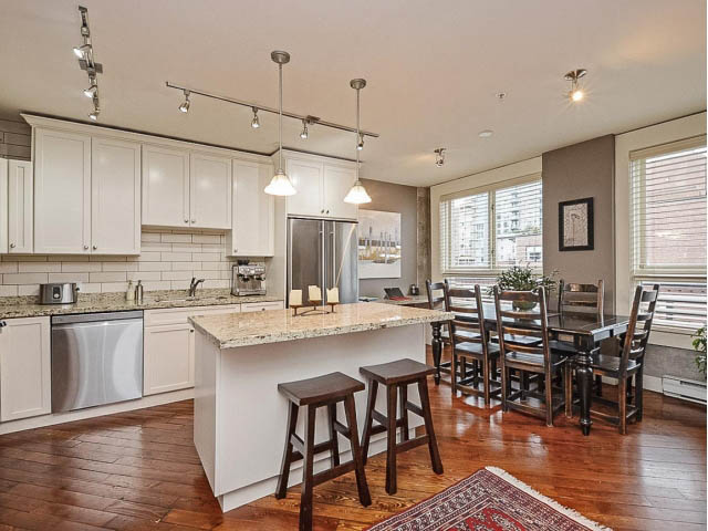 Bright kitchen with white cabinets, granite countertops, hardwood floors, and a city view. - 509 - 1216 Homer Street, Vancouver Downtown
