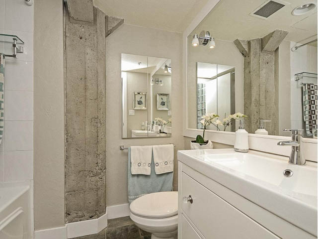 Bright bathroom with white vanity, large mirror, and concrete wall accents. - 509 - 1216 Homer Street, Vancouver Downtown