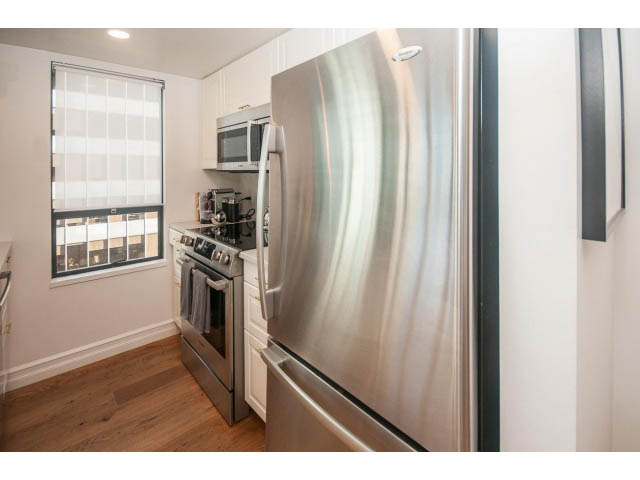 Bright kitchen with stainless steel appliances, hardwood floors, and a city view. - 1406 - 1060 Alberni Street, Vancouver Downtown