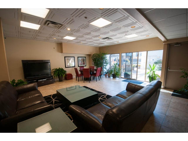 Furnished living room with leather sofas, large TV, and city view through windows. - 1406 - 1060 Alberni Street, Vancouver Downtown