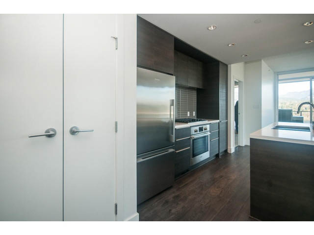 Bright kitchen with modern stainless steel appliances, dark wood cabinets, and hardwood floors. - 2401 - 1550 Fern Street, North Vancouver