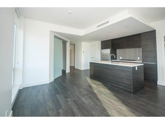 Bright kitchen with dark wood cabinets and modern countertops, featuring a large island and hardwood floors.