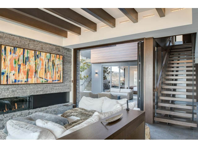 Spacious living room with modern art, large windows, and a cozy fireplace. - Address WITHHELD, Burnaby