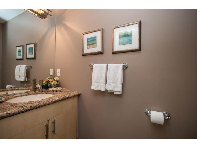 Bathroom with granite countertops, framed beach art, and towel racks. - 17 - 3750 Edgemont Boulevard, North Vancouver