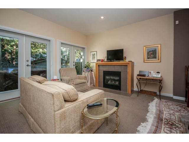 Furnished living room with cozy sofas, glass coffee table, and sliding glass doors leading to a patio. - 17 - 3750 Edgemont Boulevard, North Vancouver