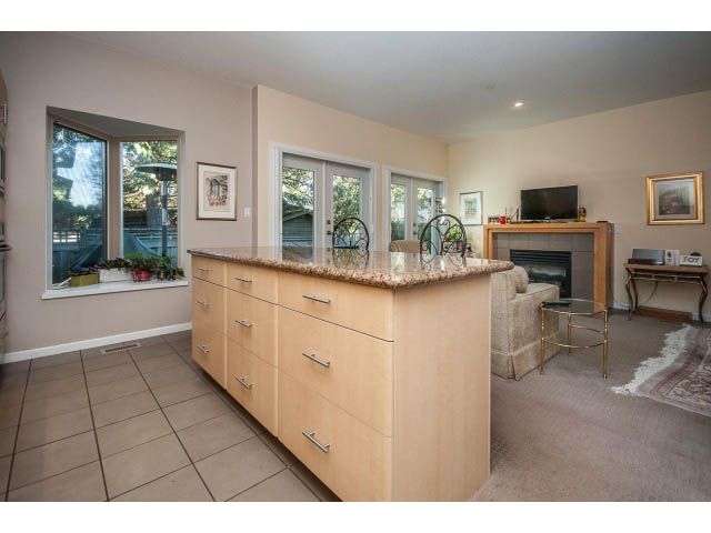 Open-concept living space with light wood cabinets, granite countertops, and sliding glass doors leading to a patio.