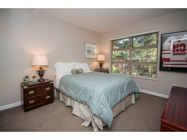 Bright bedroom with two twin beds, wooden nightstands, and a window view of greenery. - 17 - 3750 Edgemont Boulevard, North Vancouver