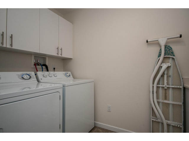 Laundry room with white appliances and wall-mounted ironing board. - 17 - 3750 Edgemont Boulevard, North Vancouver