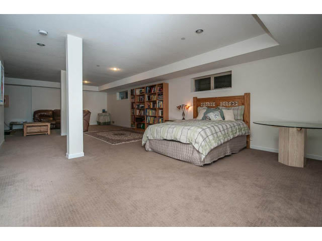 Spacious bedroom with carpeted floors, wooden headboard, and built-in bookshelf. - 17 - 3750 Edgemont Boulevard, North Vancouver