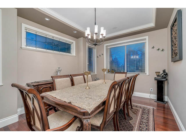 Formal dining room with hardwood floors, chandelier, and large windows. - 4287 Madeley Rd, North Vancouver