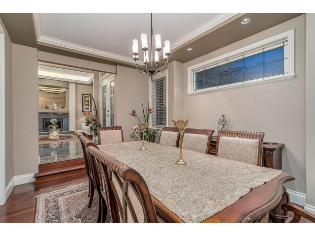 Elegant dining room with hardwood floors, chandelier, and large window. - 4287 Madeley Rd, North Vancouver