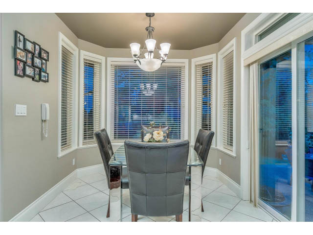 Bright dining area with large windows, white tile floors, and a chandelier. - 4287 Madeley Rd, North Vancouver