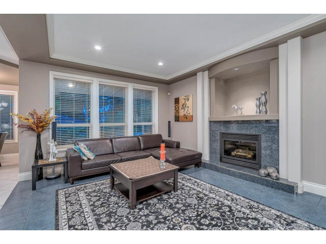 Spacious living room with modern furniture, stone countertops, and a cozy fireplace. - 4287 Madeley Rd, North Vancouver