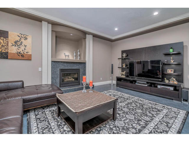 Spacious living room with modern decor, large sectional, and wall-mounted TV. - 4287 Madeley Rd, North Vancouver