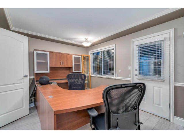 Furnished home office with wooden desk, black office chair, and blinds. - 4287 Madeley Rd, North Vancouver
