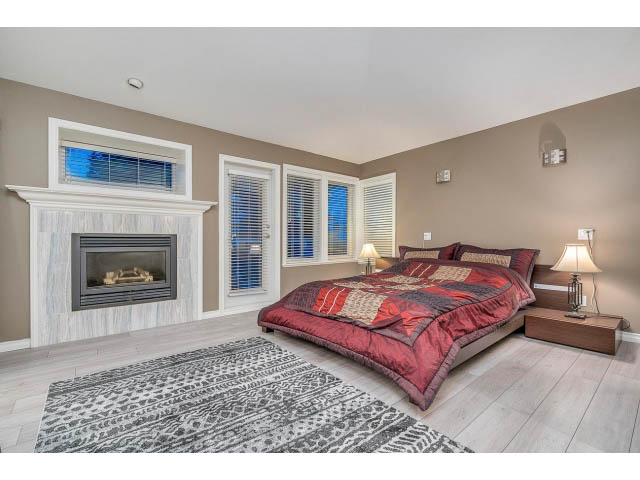 Spacious bedroom with hardwood floors, large windows, and a cozy fireplace. - 4287 Madeley Rd, North Vancouver