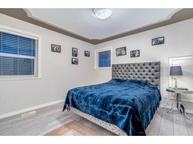 Spacious bedroom with tufted headboard, hardwood floors, and a vanity area. - 4287 Madeley Rd, North Vancouver