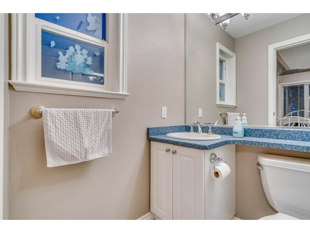 Bright bathroom with blue and white accents, modern sink, and toilet. - 4287 Madeley Rd, North Vancouver