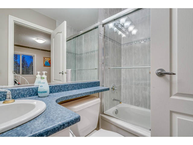 Bright bathroom with blue countertops and a walk-in shower. - 4287 Madeley Rd, North Vancouver