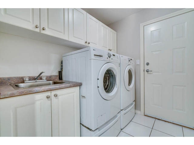 Bright laundry room with white cabinets, countertop, and tiled floor. - 4287 Madeley Rd, North Vancouver
