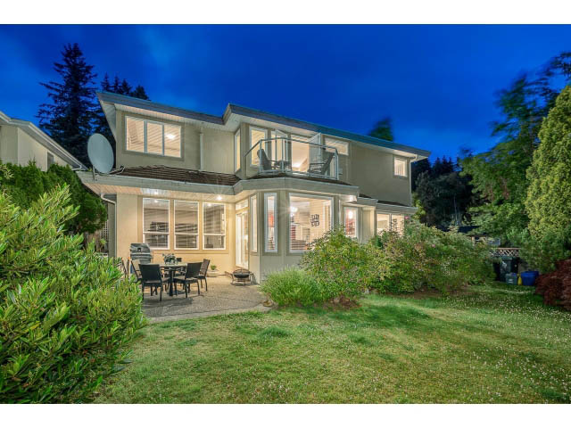 Bright living room with large windows, patio, and greenery. - 4287 Madeley Rd, North Vancouver