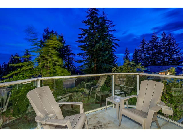 Furnished balcony with Adirondack chairs and a view of trees at dusk. - 4287 Madeley Rd, North Vancouver