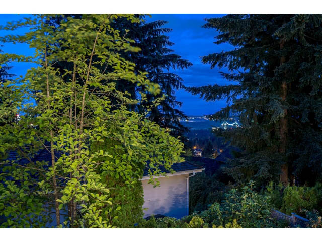 Furnished living room with city view and lush greenery. - 4287 Madeley Rd, North Vancouver