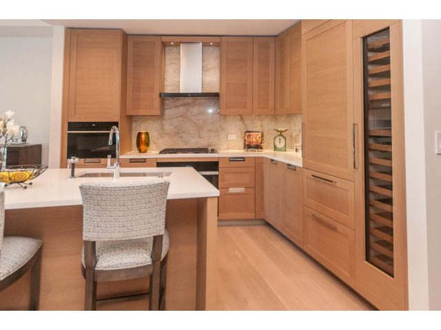 Bright kitchen with light wood cabinets, granite countertops, and a modern island. - 409 - 1355 Bellevue Ave, West Vancouver