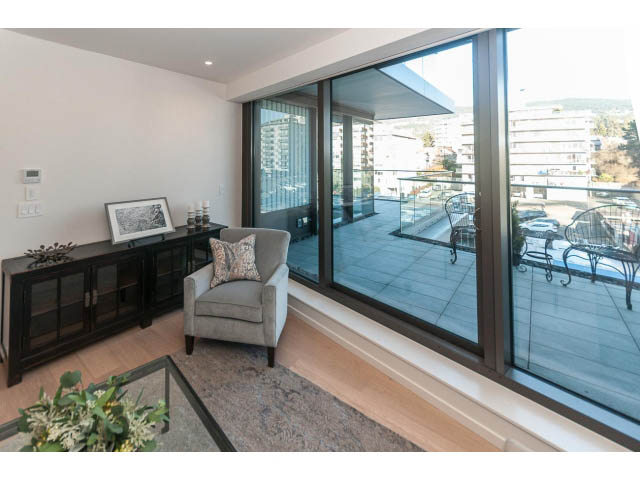 Spacious living room with large windows, hardwood floors, and city view. - 409 - 1355 Bellevue Ave, West Vancouver