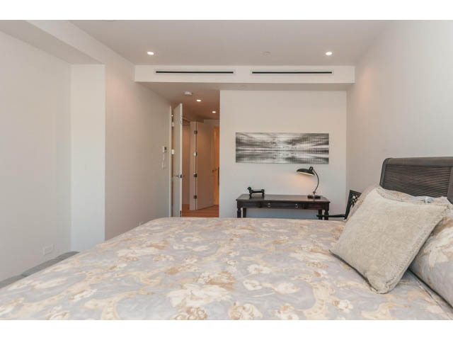 Furnished bedroom with floral bedding and modern artwork. - 409 - 1355 Bellevue Ave, West Vancouver
