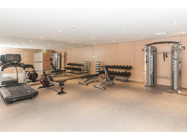 Spacious gym with treadmills, dumbbells, and weight machines. - 409 - 1355 Bellevue Ave, West Vancouver