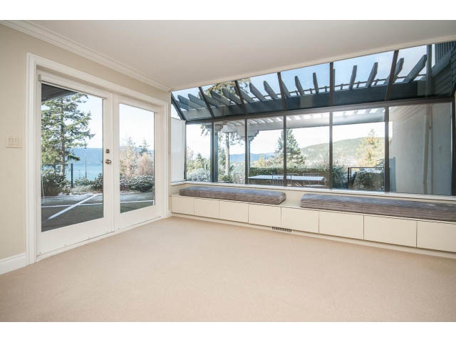 Spacious sunroom with large windows and built-in seating, offering a serene view of the outdoors. - 5138 Meadfeild Road, West Vancouver