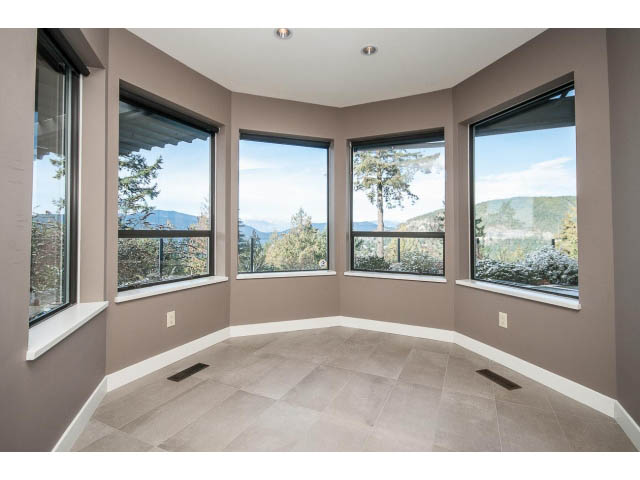 Bright sunroom with large windows offering a stunning mountain view. - 5138 Meadfeild Road, West Vancouver