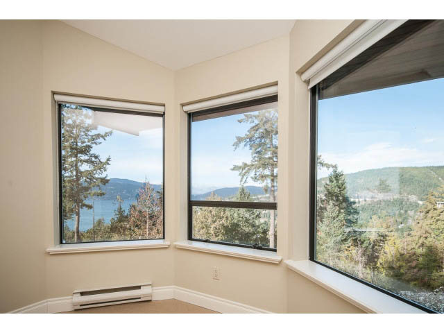 Bright living room with large windows offering a scenic view of the mountains and trees. - 5138 Meadfeild Road, West Vancouver