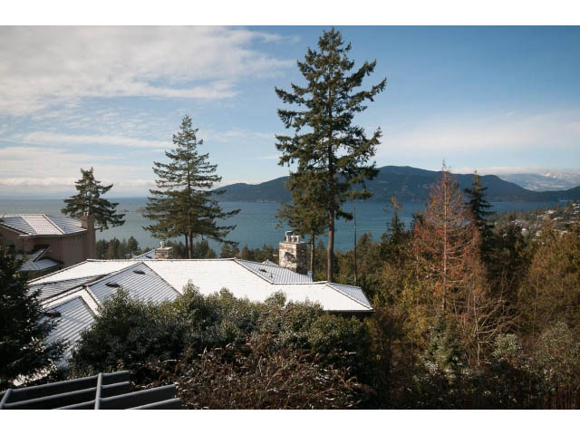 Bright living room with a stunning city view and evergreen trees. - 5138 Meadfeild Road, West Vancouver