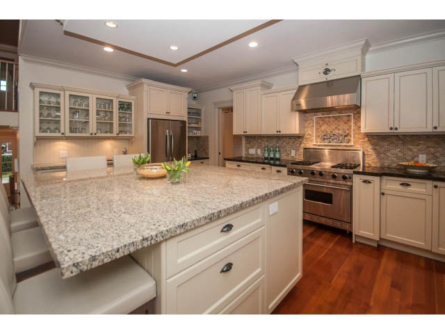 Bright kitchen with granite countertops, hardwood floors, and white cabinetry. - 840 16th East St, North Vancouver