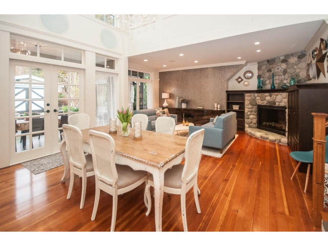 Spacious dining room with hardwood floors, large windows, and a stone fireplace. - 840 16th East St, North Vancouver