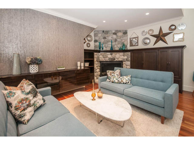 Furnished living room with stone fireplace, hardwood floors, and decorative wall art. - 840 16th East St, North Vancouver